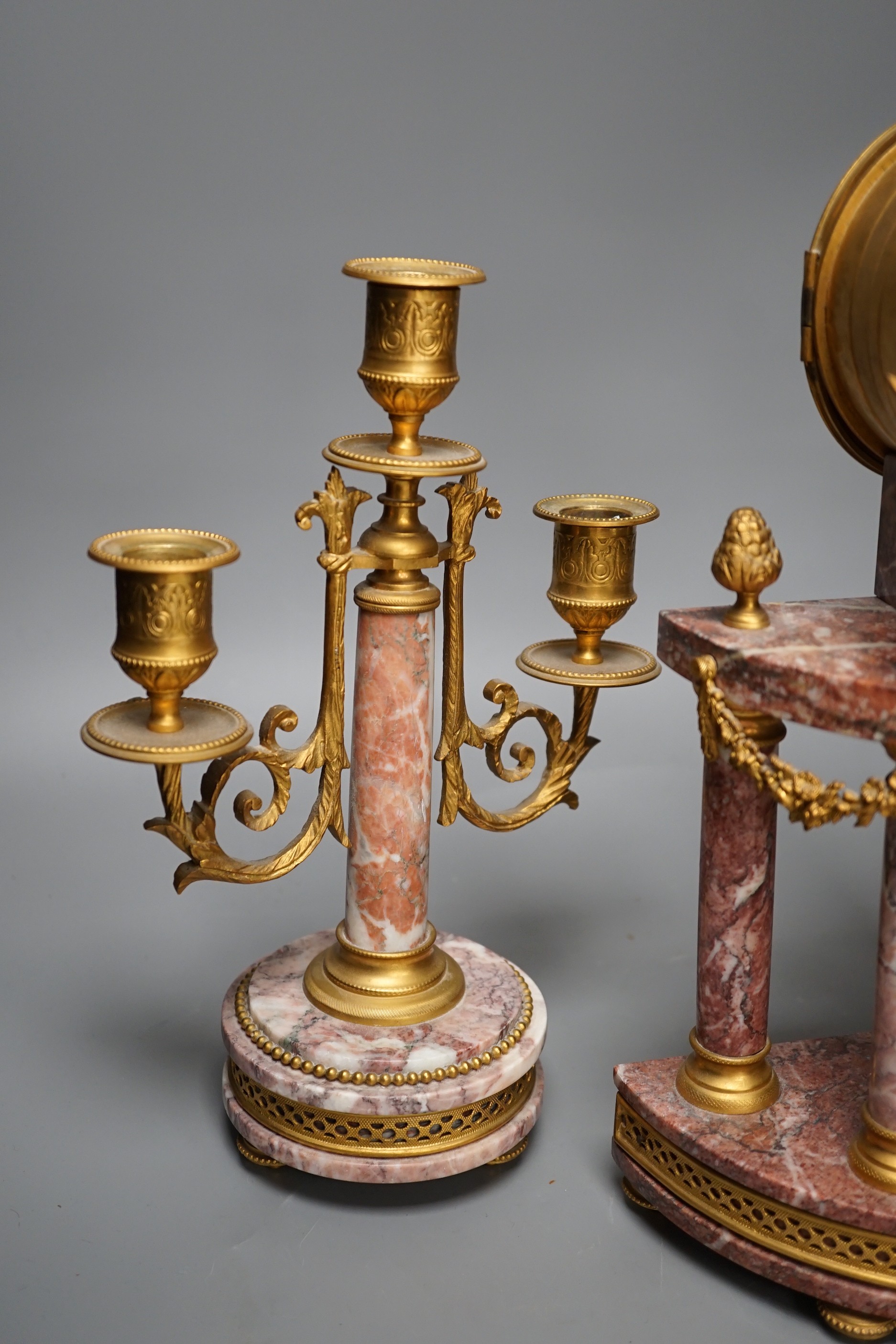 A French ormulu and rouge marble clock garniture, c.1900, with decorative enamel dial, 40cms high.